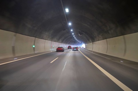 Motorway tunnel with several cars, illuminated by overhead lights, Switzerland, Europe