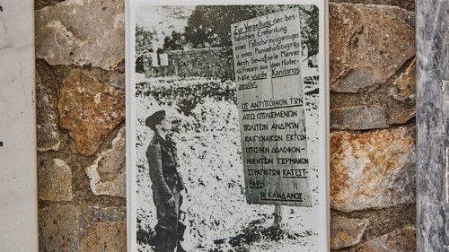 Black and white photo of a soldier on a memorial plaque on a stone wall, visit of Federal President