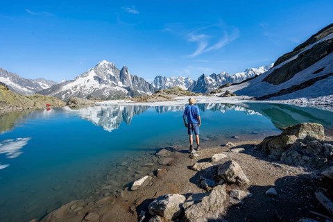 Mountaineer in front of mountain landscape with mountain lake, tourist at Lac Blanc with water