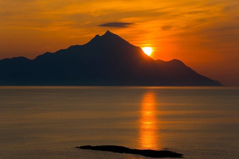 Dramatic sunrise over the mountains with golden reflections on the sea, majestic silhouette, view