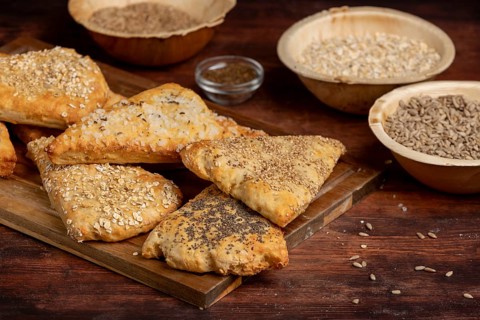 Freshly baked dough triangles sprinkled with sunflower seeds, poppy seeds, sesame seeds, oat flakes