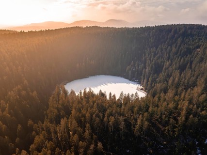 Aerial view of a circular lake in the midst of wintry fog and forest landscapes, Glaswaldsee, Bad