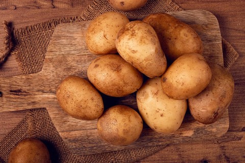Raw potatoes, scattered on a chopping board, close-up, no people