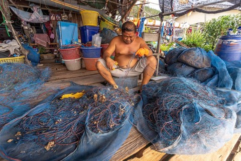 Fisherman repairing his net, fishing village Ban Ao Salad, island Ko Kut or Koh Kood in the Gulf of