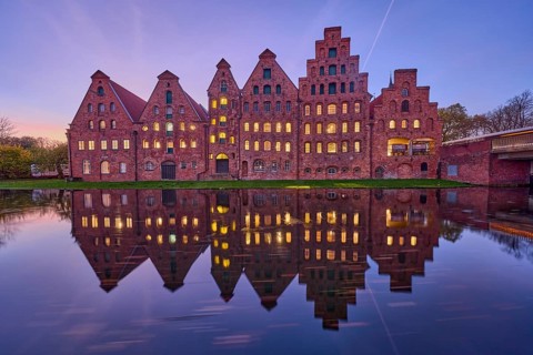 Historic salt warehouses, brick buildings, illuminated windows, symmetrical reflections on the