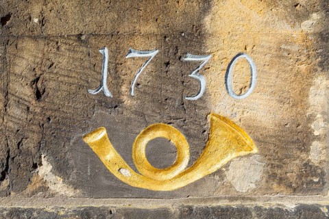 Year 1730 and post horn in gold, detail on the historic post milestone column near the castle in