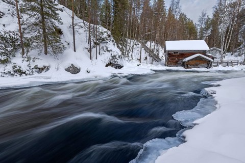 Old wooden Myllykoski water mill along the river Kitkajoki in winter, Oulanka National Park,