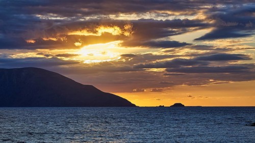 A dramatic sunset with clouds over the sea, an island on the horizon at dusk, sunset, Kassos,