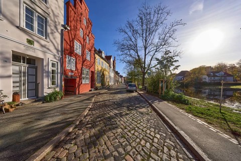 Historic houses, cobblestone pavement, bare trees, river Trave, backlight of the sun, street, old