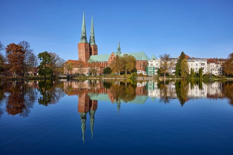 Mill pond with general buildings, Lübeck Cathedral and trees, symmetrical reflections on the water