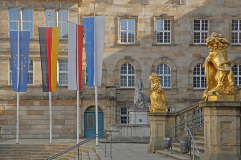 Town hall built in 1909 with flags and two golden lion figures, EU flag, German national flag,