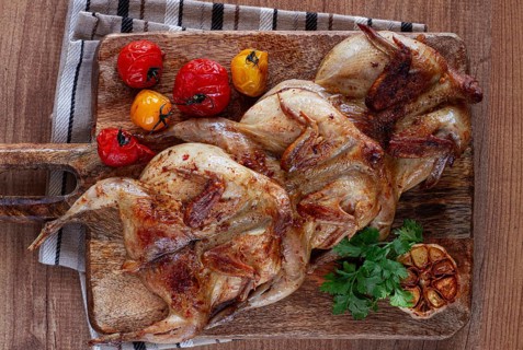 Grilled quail meat, on a wooden chopping board, tobacco, in the oven, with spices, homemade,