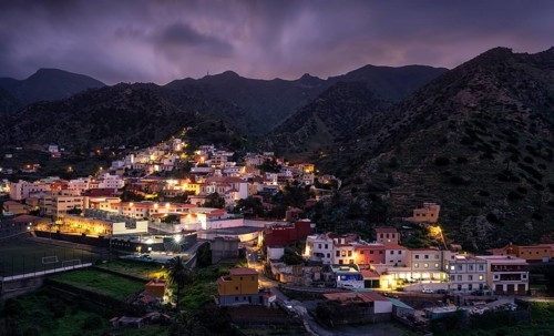 View of Vallehermoso and the surrounding mountain landscape at dusk under a cloudy sky. The street