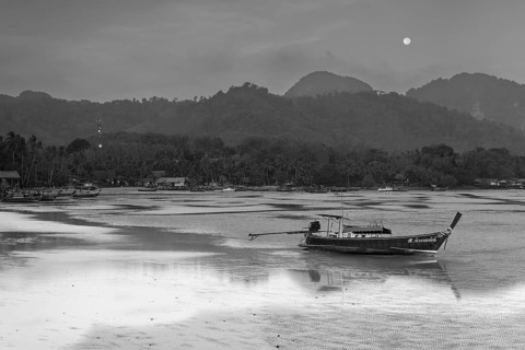 Before sunrise, longtail boats lie at low tide in the harbour at Sivalai Beach, Koh Mook Island,