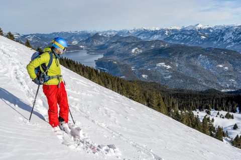Skiers skiing down the Simetsberg, view of Walchensee and mountain panorama, Estergebirge, Bavarian