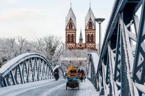 Bridge with snow and ice and cyclists, Blue Bridge and Stühlinger Church, Freiburg im Breisgau,