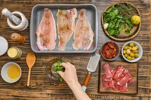 View from above on the hand putting fresh basil in the bowl of the immersion blender. Preparation