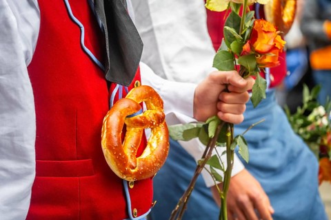 Parade of historically costumed guild members, guild member wearing a pretzel around his neck,