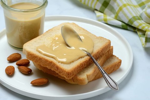 Almond cream on toast, almonds and spoon