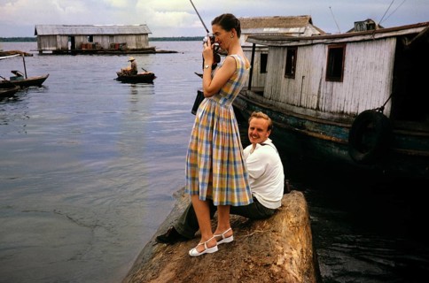 Tourists visiting an area of informal shelters where wooden huts are built on logs, known as the