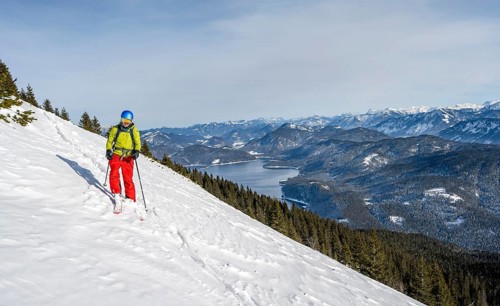Skiers skiing down the Simetsberg, view of Walchensee and mountain panorama, Estergebirge, Bavarian