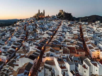 The hilltop White Town of Olvera with its La Encarnación church and Moorish castle. At dusk. Aerial