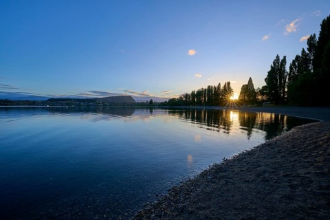 Calm lake at sunrise with clear reflection of the trees and slightly cloudy sky, summer, Lake