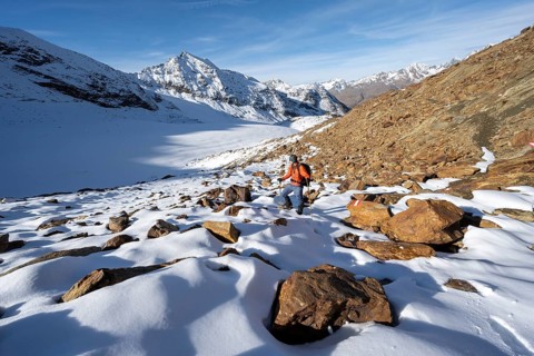 Mountaineer on a hiking trail with snow, descent from Ramoljoch at Spiegelferner, autumnal mountain