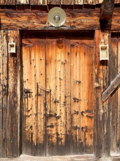 Entrance door of a rustic old weathered alpine hut decorated with butter moulds, East Tyrol,