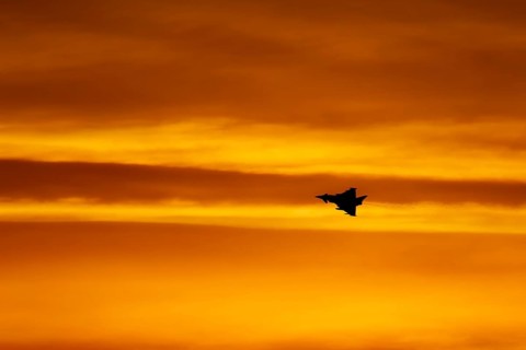 Eurofighter Typhoon silhouette of aircraft in RAF Royal air force colours flying at sunset,