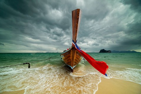 Longtail boat on the beach, dark rain clouds behind, Koh Ngai Island, Andaman Sea, Satun Province,