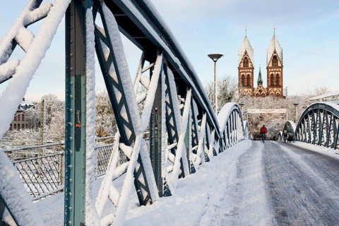 Bridge with snow and ice and cyclists, Blue Bridge and Stühlinger Church, Freiburg im Breisgau,