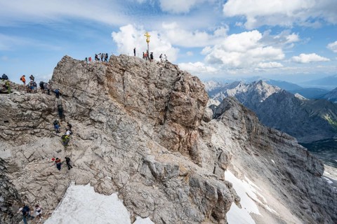 Tourists queue up for the summit of the Zugspitze, summit with golden summit cross, overtourism,
