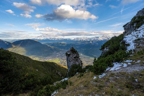 Rocky peak with summit cross, view of Garmisch-Partenkirchen and mountain panorama, hike to