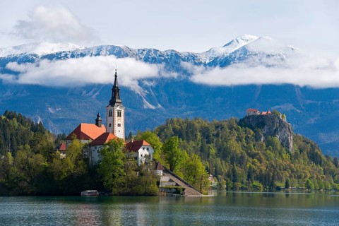 Church on a wooded island in a lake, with mountains in the background, Bled Island with St Mary's