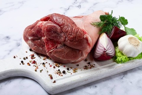 Raw pork knuckle, on a wooden chopping board, with spices, close-up, top view, no people