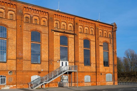 Brick building with large windows and metal staircase in front of a clear blue sky, blower hall,