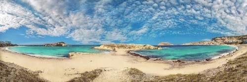 Wide panorama of Frangolimiona sandy beach with turquoise sea and slightly cloudy sky, Arkasa,