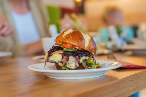 A juicy burger with vegetables served on a pretzel bun in the restaurant, autumn creations, Cafe