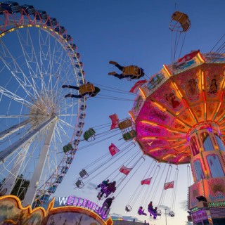 A funfair at dusk with illuminated chain carousel and Ferris wheel, Europa Rad, rides, wave flight,