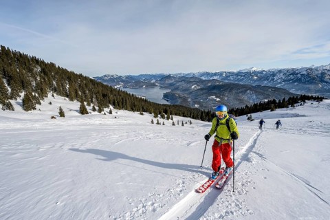 Ski tourers ascending Simetsberg, view of Walchensee and mountain panorama, Estergebirge, Bavarian
