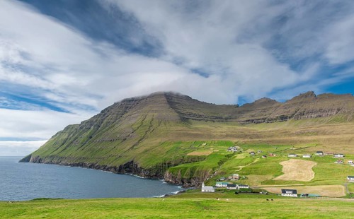 Coastal landscape with mountains and village under blue sky, Vidareidi, Vidoy Island, Viðareiði,