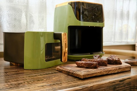 A stylish kitchen corner showcases an air fryer beside a cooking unit. Juicy pieces of grilled meat