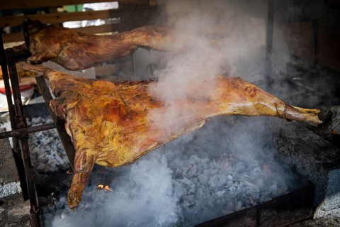 Traditionally grilled pork halves over charcoal, surrounded by smoke in a rustic setting, Medieval