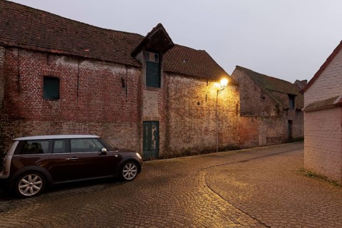 Modern Mini Clubman parked in an old village alleyway with brick buildings, twilight, Damme, West