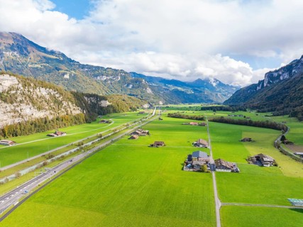 Wide valley with green meadows and a road, framed by mountains, Lake Brienz, Switzerland, Europe
