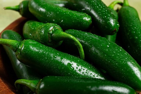 Fresh padron pepper, raw, in a wooden bowl, on the table, there are no people