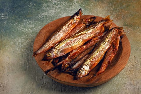 Cold smoked capelin, on a wooden bowl, top view, no people
