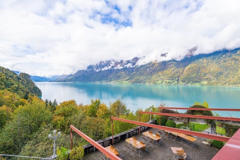 View of a lake with surrounding mountains and a terrace with tables, Lake Brienz, Switzerland,