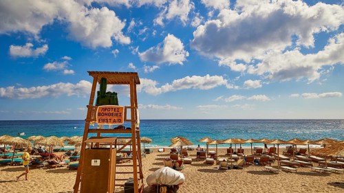 A lifeguard tower on the beach surrounded by parasols and sunbeds, with a sweeping view of the sea